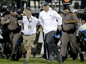 Central Florida coach Scott Frost, center, runs onto the field after the team defeated South Florida 49-42 in an NCAA college football game, Friday, Nov. 24, 2017, in Orlando, Fla. (AP Photo/John Raoux)
