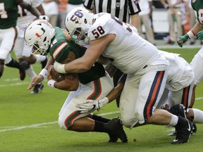 Miami quarterback Malik Rosier, left, is tackled by Virginia defensive end Eli Hanback (58) during the first half of an NCAA college football game, Saturday, Nov. 18, 2017, in Miami Gardens, Fla. (AP Photo/Lynne Sladky)