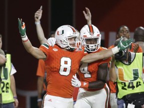 Miami wide receiver Braxton Berrios (8) celebrates with wide receiver Jeff Thomas (4) after scoring a touchdown during the first half of an NCAA college football game against Notre Dame, Saturday, Nov. 11, 2017, in Miami Gardens, Fla. (AP Photo/Lynne Sladky)