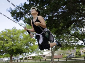 In this Thursday, April 28, 2016 photo, Theo Ramos, 14, plays on a swing set at his neighborhood park in Homestead, Fla. Ramos, always a tomboy before he even knew what the word transgender meant, feels more like a boy. But experts agree that any transitioning teen's journey is difficult and fraught with indecision, anxiety and worry _ by the teens as well as their parents. (AP Photo/Lynne Sladky)