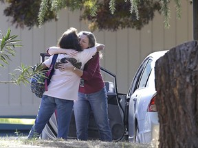 FILE - In this Nov. 14, 2017 file photo, two women embrace outside Rancho Tehama Elementary School, where a gunman opened fire in Corning, Calif. Sheriff's deputies responded 21 times in the last year to calls involving a California man who had been feuding with his neighbors before he committed a shooting rampage last week, killing five people and wounding at least eight others. . (AP Photo/Rich Pedroncelli, File)