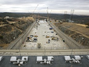 FILE - In this Oct. 19, 2017 photo, crews work to repair the damaged main spillway of the Oroville Dam in Oroville, Calif. California state officials say small cracks that have appeared in the brand new concrete spillway at Oroville Dam were expected and do not pose a threat. Previously undisclosed letters show federal regulators asked Department of Water Resources officials to explain the hairline cracks on the dam's new massive concrete flood-control chute. (AP Photo/Rich Pedroncelli, File)