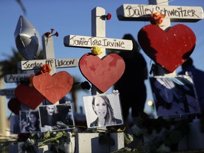 FILE - In this Oct. 6, 2017 file photo, a woman passes crosses for victims of the mass shooting in Las Vegas. Some victims injured in the Las Vegas mass shooting are asking a committee in charge of distributing donations to rework a plan that would be used to divide the money. The committee heard from victims and their relatives Tuesday, Nov. 28, 2017, during an emotional meeting. (AP Photo/Gregory Bull, File)