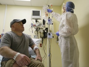 In this photo taken Monday, Nov. 13, 2017, Brian Madeux, 44, looks up at nurse practitioner Jacqueline Madde while receiving the first human gene editing therapy at the UCSF Benioff Children's Hospital in Oakland, Calif.  Madeux, who has a metabolic disease called Hunter syndrome, will receive billions of copies of a corrective gene and a genetic tool, through an IV,  to cut his DNA in a precise spot.