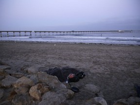 A person sleeps under a blanket on a beach near the Ocean Beach Pier in San Diego on Sept. 28, 2017. A homeless crisis of unprecedented proportions is rocking the West Coast, leaving elected officials and outreach workers scrambling for solutions. (AP Photo/Gregory Bull)