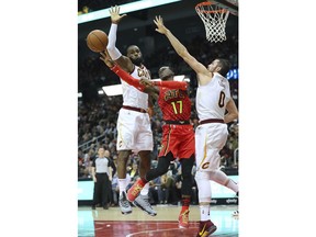 Atlanta Hawks guard Dennis Schroder passes off under the basket on a double team by Cleveland Cavaliers LeBron James and Kevin Love during the first half of an NBA basketball game, Thursday, Nov. 30, 2017, in Atlanta. (Curtis Compton/Atlanta Journal-Constitution via AP)
