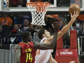 New York Knicks forward Doug McDermott, right,  shoots a reverse lay up on Atlanta Hawks center Dewayne Dedmon, left, during the first half of a NBA basketball game, Friday, Nov.24, 2017, in Atlanta. (AP Photo/John Amis)