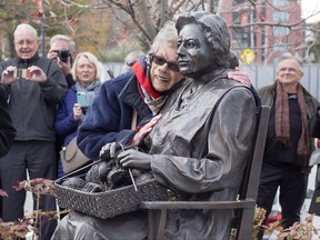 Charlotte Guy Jeffries embraces the sculpture, The Seated Woman, one of three, as the Halifax Women's History Society officially unveils a bronze monument, The Volunteers/Les Benevoles, to pay tribute to women volunteers during the Second World War, in Halifax on Thursday, Nov. 16, 2017. Jeffries was an accomplished musician who entertained troops during the war effort. THE CANADIAN PRESS/Andrew Vaughan