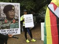 People hold their messages in Harare to demonstrate for the ouster of President Robert Mugabe who is virtually powerless and deserted by most of his allies, Saturday, Nov. 18, 2017.