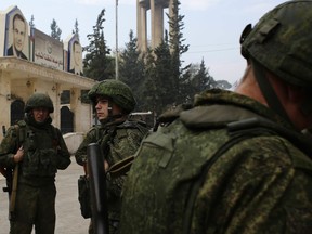 FILE - In this Dec. 4, 2016 file photo, Russian soldiers stand next to an aid convoy in Aleppo, Syria. After watching for years as the United States called the shots in the region, Russian President Vladimir Putin is seizing the reins of power in the Middle East, establishing footholds and striking alliances with unlikely partners. From Syria's battlefields to its burgeoning partnership with Iran and Turkey to its deepening ties with Saudi Arabia, Russia is stepping in to fill a void left by the United States. (AP Photo/Hassan Ammar, File)