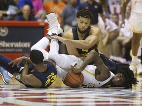 Marquette forward Jamal Cain (23) and teammate forward Theo John (4) try to wrestle a loose ball away Virginia Commonwealth forward Issac Vann (11) during the first half of an NCAA college basketball game, Monday, Nov. 20, 2017, in Lahaina, Hawaii. (AP Photo/Marco Garcia)