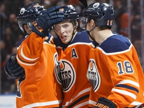 Oilers' Matthew Benning, left, Ryan Nugent-Hopkins, centre, and Ryan Strome celebrate the overtime-winning goal against the Arizona Coyotes during their game in Edmonton on Tuesday night.