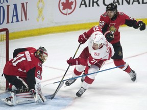 Detroit Red Wings' Dylan Larkin has his path to the net blocked by Senators goalie Craig Anderson while Mike Hoffman helps defend during second period NHL action Thursday night in Ottawa.