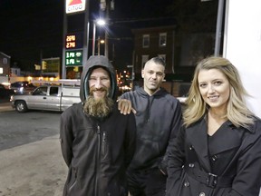 In this Nov. 17, 2017, photo, Johnny Bobbitt Jr., left, Kate McClure, right, and McClure's boyfriend Mark D'Amico pose at a Citgo station in Philadelphia.