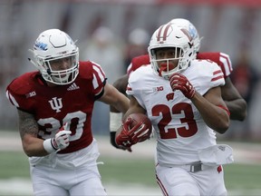 Wisconsin's Jonathan Taylor (23) is chased by Indiana's Chase Dutra (30) during the first half of an NCAA college football game, Saturday, Nov. 4, 2017, in Bloomington, Ind. (AP Photo/Darron Cummings)