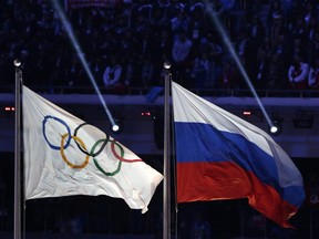 In this Feb. 23, 2014 file photo, the Russian national flag, right, flies after it is hoisted next to the Olympic flag during the closing ceremony of the Winter Olympics in Sochi.