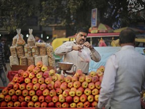 In this Nov. 15, 2017, photo, Ajay Kumar, 46, a fruit vendor sells apples outside a railway station in New Delhi, India. Kumar has been doing this job for more than 30 years, supporting his wife and four children. He said on days this month when the pollution has been bad he's covered his face and worn goggles. And the smog made him ill. "I had a fever and a cough. My eyes hurt, my throat hurt and it was difficult to walk," he said. "But I still had to muster the courage to work for my children, to feed them. Work has to be done. Work is important." (AP Photo/Altaf Qadri)
