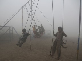 Children ride swings in a playground surrounded by smog in Lahore, Pakistan, Saturday, Nov. 11, 2017. Smog has enveloped much of Pakistan, causing highway accidents and respiratory problems, and forcing many residents to stay home, officials said. (AP Photo/K.M. Chaudary)