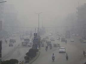 Motorcycles and vehicles are driven on a road while fog envelopes the area in Peshawar, Pakistan, Sunday, Nov. 5, 2017.  Smog has enveloped much of Pakistan and neighboring India, causing highway accidents and respiratory problems, and forcing many residents to stay home, officials said. (AP Photo/Muhammad Sajjad)