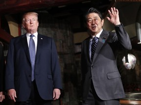 Japanese Prime Minister Shinzo Abe waves while arriving with U.S. President Donald Trump for a dinner at Ginza Ukai Tei restaurant in Tokyo on Nov. 5.