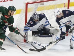 Jets goalie Connor Hellebuyck and defenceman Tyler Myers, team up to stop the Wild's Joel Eriksson Ek during the third period of their game Tuesday night in St. Paul, Minn. The Jets won 2-1.