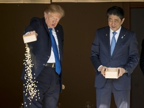 President Donald Trump pours the remainder of his fish food out as he and Japanese Prime Minister Shinzo Abe feed fish in a koi pond at the Akasaka Palace, Monday, Nov. 6, 2017, in Tokyo. Trump is on a five country trip through Asia traveling to Japan, South Korea, China, Vietnam and the Philippines. (AP Photo/Andrew Harnik)