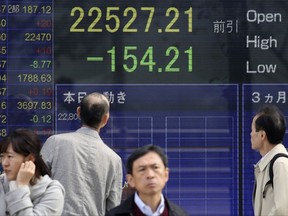 People look at an electronic stock board of a securities firm in Tokyo, Monday, Nov. 13, 2017. Asian stock markets were mixed Monday following Wall Street's losing week as investors looked ahead to a week of data releases and public comments by central bankers. (AP Photo/Koji Sasahara)
