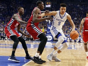 Kentucky's Kevin Knox (5) looks for an opening on Illinois-Chicago's Tai Odiase, middle, and Dikembe Dixson (10) during the first half of an NCAA college basketball game, Sunday, Nov. 26, 2017, in Lexington, Ky. (AP Photo/James Crisp)
