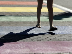 In this June 20, 2017 photo, a pedestrian crosses Short Street at North Limestone Avenue in Lexington, Ky. The rainbow-colored crosswalk honoring the LGBT community in Lexington is a distracting safety hazard and should be removed, a federal official says.  Officials painted the crosswalk at a busy intersection across from the county courthouse earlier this year to coincide with an annual gay pride festival. At the time, city officials said the crosswalk would be safer because it would better catch the attention of drivers. (Pablo Alcala/Lexington Herald-Leader via AP)