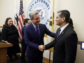 FILE - In this Aug. 14, 2017 file photo, California Attorney General Xavier Becerra, right, shakes hands with San Francisco City Attorney Dennis Herrera during a press conference at San Francisco City Hall. They announced that state and the city and county of San Francisco are suing the U.S. Department of Justice over President Donald Trump's sanctuary city restrictions on public safety grants. A federal judge Monday, Nov. 20, 2017 has permanently blocked President Donald Trump's executive order to cut funding from cities that limit cooperation with U.S. immigration authorities. San Francisco and Santa Clara County had filed lawsuits. (AP Photo/Marcio Jose Sanchez, File)