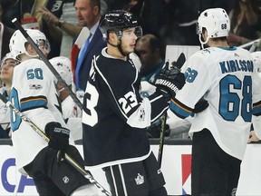 Los Angeles Kings right wing Dustin Brown, center, celebrates scoring a power play goal as he skates past San Jose Sharks' Chris Tierney, left, and Melker Karlsson, right, during the first period of an NHL hockey game, Sunday, Nov. 12, 2017, in Los Angeles. (AP Photo/Danny Moloshok)