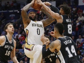 New Orleans Pelicans center DeMarcus Cousins (0) powers past San Antonio Spurs guard Patty Mills (8), guard Danny Green (14) and center Pau Gasol (16) for a dunk in the first half of an NBA basketball game in New Orleans, Wednesday, Nov. 22, 2017. (AP Photo/Scott Threlkeld)