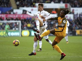 Swansea City's Tom Carroll, left, and Brighton & Hove Albion's Gaetan Bong battle for the ball during the English Premier League soccer match at the Liberty Stadium, Swansea, Wales, Saturday Nov. 4, 2017. (Nick Potts/PA via AP)