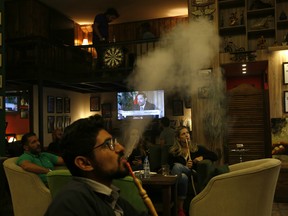 Lebanese smoke water pipes at a coffee shop as they listen to outgoing Lebanese Prime Minister Saad Hariri during a live interview shown on his Future TV from Saudi Arabia.