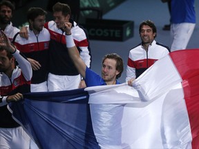 France's Lucas Pouille, center, carries the French flag with teammates after he defeated Belgium's Steve Darcis in their Davis Cup final single match at the Pierre Mauroy stadium in Lille, northern France, Sunday, Nov. 26, 2017. France won the Davis Cup for the first time in 16 years after Lucas Pouille beat Belgium's Steve Darcis to clinch the decisive point of the final. (AP Photo/Michel Spingler)