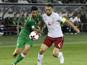 FILE - In this Saturday, Sept. 2, 2017 file photo, Republic of Ireland's Shane Long, left, struggles for the ball with Georgia's Guram Kashia during their World Cup Group D qualifying soccer match at the Boris Paichadze Dinamo Arena in Tbilisi, Georgia. Eight people have been arrested after a far-right group in Georgia gathered to demand a soccer player be kicked off the national team for taking part in a gay rights initiative. The nationalist Georgian March group wants defender Guram Kashia punished for wearing a rainbow armband while captaining Dutch club Vitesse Arnhem in early Oct. 2017. (AP Photo/Shakh Aivazov, file)