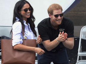 FILE - In this Monday, Sept. 25, 2017 file photo, Britain's Prince Harry and his girlfriend Meghan Markle attend the wheelchair tennis competition during the Invictus Games in Toronto. Palace officials announced Monday Nov. 27, 2017, Prince Harry and Meghan Markle are engaged, and will marry in the spring. (Nathan Denette/The Canadian Press via AP, File)