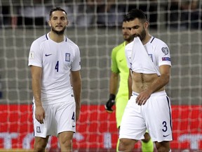FILE - In this Sunday, Sept. 3, 2017 file photo, Greece's Kostas Manolas, left, and Giorgos Tzavellas, right, react after Belgium scored the opening goal during their World Cup Group H qualifying soccer match at Georgios Karaiskakis Stadium in Piraeus port, near Athens. FIFA has suspended Greece defender Kostas Manolas for a World Cup playoff next week for trying to manipulate his disciplinary record, it was announced on Friday, Nov. 3. FIFA says Manolas was judged guilty of "intentionally seeking a yellow card" in a World Cup qualifying game. It triggered a one-match ban which he served in Greece's final qualifier that cleaned his record for the playoffs.(AP Photo/Thanassis Stavrakis, file)
