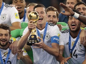 FILE  - In this Sunday, July 2, 2017 file photo, Germany's Julian Draxler holds up the trophy, at the end of the Confederations Cup final soccer match between Chile and Germany, at the St.Petersburg Stadium, Russia. The Global Nations League being proposed by UEFA can revive international soccer. Out go most irrelevant friendlies. In come more meaningful fixtures with silverware at stake at the end of it in June 2021. Even smaller countries get a chance to pick up a trophy. But it's a complex format for fans to understand. And world governing body FIFA has its own plans for June 2021, staging a first 24-team Club World Cup expanded from the existing annual seven-team event. (AP Photo/Ivan Sekretarev, File)