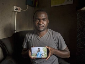 Patson Dzamara poses with a photograph of his missing brother, Zimbabwean activist Itai Dzamara, in his brother's house in Harare, Tuesday, Nov. 28, 2017. Itai Dzamara was abducted by suspected state agents in 2015 after urging then-President Robert Mugabe to resign. (AP Photo/Bram Janssen)