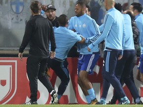 FILE - In this Thursday, Nov. 2, 2017 file photo, Marseille's Patrice Evra, third left, raises his foot trying to kick a man during a scuffle with Marseille supporters who trespassed onto the field before the Europa League group I soccer match between Vitoria SC and Olympique de Marseille at the D. Afonso Henriques stadium in Guimaraes, Portugal. UEFA has suspended Marseille defender Patrice Evra until June 2018 for kicking one his own team's fans before a Europa League game. (AP Photo/Luis Vieira, File)
