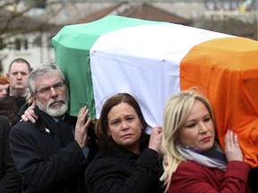 FILE - In this Thursday, March 23, 2017 file photo, Sinn Fein's Gerry Adams, left, Mary Lou McDonald, centre, and Michelle O'Neill carry the coffin of former IRA commander and Sinn Fein deputy leader Martin McGuinness to St Columba's Church in Londonderry, Northern Ireland. Gerry Adams has announced that he plans to step down as leader of Sinn Fein next year after heading the party for over 30 years. Adams said in a speech at the party's annual conference in Dublin on Saturday, Nov. 18, 2017 that he will not stand for the next Irish parliamentary election. (AP Photo/Peter Morrison, file)