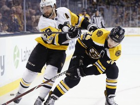 Boston Bruins' Jake DeBrusk (74) and Pittsburgh Penguins' Kris Letang (58) battle for the puck during the first period of an NHL hockey game in Boston, Friday, Nov. 24, 2017. (AP Photo/Michael Dwyer)