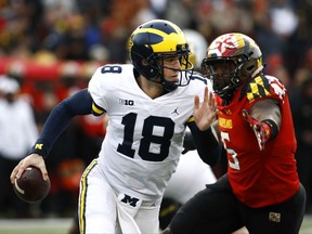 Michigan quarterback Brandon Peters (18) looks for a receiver as he is pressured by Maryland defensive lineman Cavon Walker in the first half of an NCAA college football game in College Park, Md., Saturday, Nov. 11, 2017. (AP Photo/Patrick Semansky)