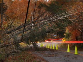 A car leaves a trail of light as it passes under power lines weighed down by toppled trees in Freeport, Maine, Tuesday, Oct. 31, 2017. Utility crews scrambled to restore power throughout New England on Tuesday, one day after a severe storm packing hurricane-force wind gusts and torrential rain. (AP Photo/Robert F. Bukaty)