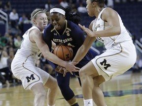 Notre Dame guard Arike Ogunbowale (24) squeezes between Michigan guard Nicole Munger, left, and forward Jillian Dunston during the first half of an NCAA college basketball game, Wednesday, Nov. 29, 2017, in Ann Arbor, Mich. (AP Photo/Carlos Osorio)