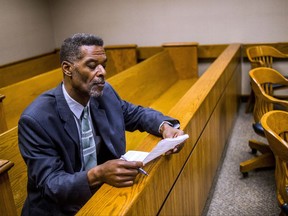 FILE - In this Aug. 23, 2017 file photo, Flint City Councilman Eric Mays looks over paperwork before Judge William H. Crawford arraigns him in Genesee District Court, in Flint, Mich. Mays, accused of pawning his publicly owned laptop nine times, has been ordered to pay $300 and put in a week's worth of service on a sheriff's work detail. Mays learned his punishment Monday, Nov. 27, 2017, after pleading no contest in August to misdemeanor willful neglect of duty. (Jake May/The Flint Journal-MLive.com via AP, File)