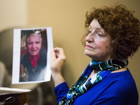 Witness Maryanne Tribble holds a photo of her father, John Snyder, who died of Legionnaire's disease in 2015, during the preliminary examination of Dr. Eden Wells, chief medical executive of the Michigan Department of Health and Human Services, on Monday, Nov. 6, 2017, in Genesee County District Court in downtown Flint, Mich. Wells faces charges of manslaughter, obstructing justice, lying to an investigator and misconduct in office in connection with her handling of the Flint water crisis. The water crisis has been linked to lethal outbreaks of Legionnaire's disease in Flint in 2014 and 2015. (Terray Sylvester/The Flint Journal-MLive.com via AP)
