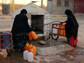 A Thursday Oct. 19, 2017 photo of Moroccan women filling up containers with water from a hose, in Zagora, southeastern Morocco.