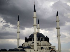 In this photo taken on Thursday, Nov. 1, 2017,  a man clambers over a metal dome, bottom, as construction works continue in the Hala Sultan mosque outside of the divided capital Nicosia, in the Turkish occupied northern part of the Island of Cyprus.  A resurgence of Islam in breakaway northern Cyprus with the construction of scores of new mosques has some Turkish Cypriots fearing that their secular way of life is being assailed, but religious leaders dismiss such fears as unfounded. (AP Photo/Petros Karadjias)